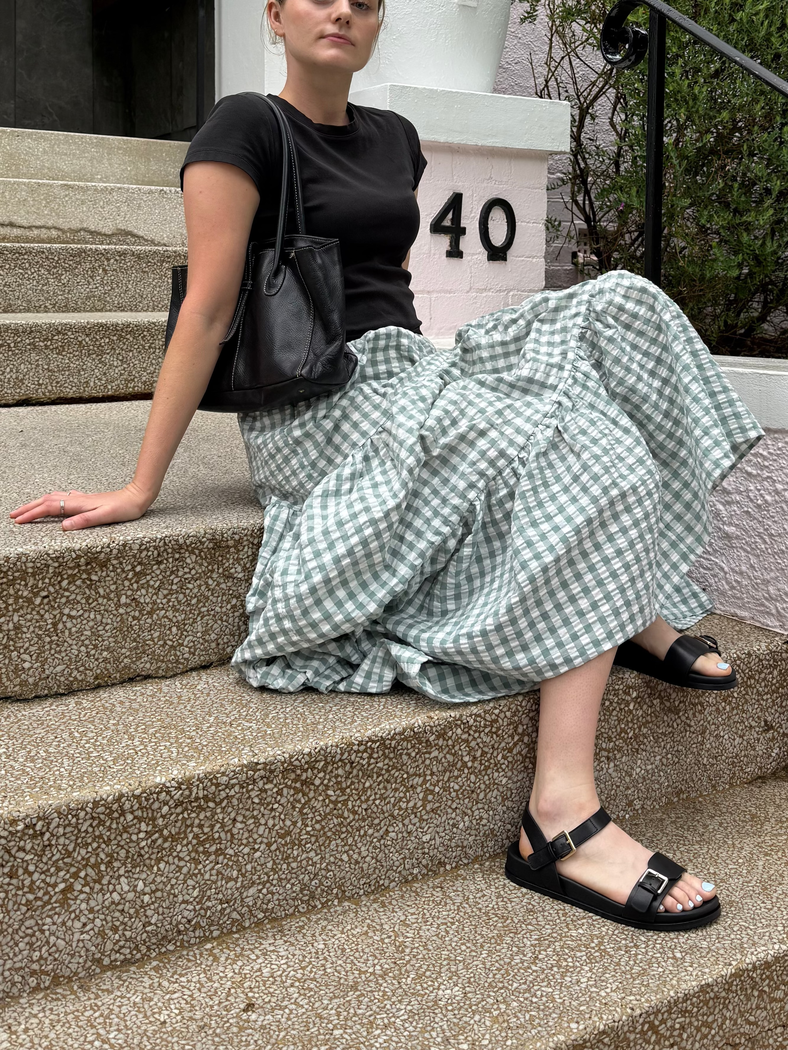 Woman sitting on steps in front of a building with a number '40'.